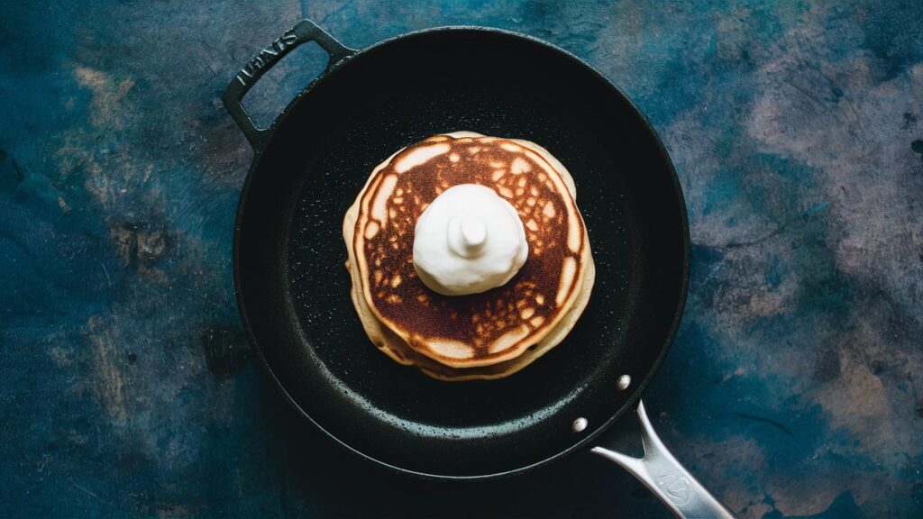 Non-stick pan with a golden-brown pancake being flipped.